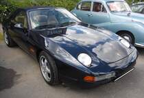 Porsche 928 GTS. Bei der Konstruktion des ab 1978 produzierten 928 stand der Leichtbau im Vordergrund. So wurden die Türen, die vorderen Kotflügel sowie die Motorhaube aus Aluminium statt aus Stahlblech gefertigt. Der 928 hat runde, in die Kotflügel integrierte Hauptscheinwerfer, die elektrisch hochklappbar sind. Das abgerundete Fließheck wird von der großen Scheibe der Heckklappe dominiert. Der gezeigte 928 GTS war die letzte Entwicklungsstufe dieser Baureihe. Er hat verbreiterte hintere Kotflügel, ein rotes Leuchtenband am Heck, einen in Wagenfarbe lackierten Heckflügel, Außenspiegel im Cup-Design sowie serienmäßig 17-Zoll Cup-Felgen. Der V8-Motor hat einen Hubraum von 5397 cm³ und leistet 350 PS. Die Zuffenhausener gaben die Höchstgeschwindigkeit mit 275 km/h an. Bei seinem Verkaufsstart im Jahr 1992 betrug der Basispreis für einen solchen 928 GTS DM 85.840,00. 16. Oldtimer-Festival an der  Alten Dreherei  in Mülheim an der Ruhr am 15.06.2024.