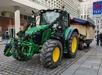 =John Deere 6120 M hat den Anhänger mit dem Riesenstollen am Haken beim Stollenfestzug in Dresden, 12-2024
