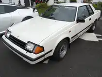 Toyota Celica der vierten Generation (Baureihe RA63). 1982 - 1985. Der Modellwechsel zum Jahresanfang 1982 hätte radikaler nicht sein können. Keilförmig, mit weit herabgezogener Bugpartie und nach vorn klappbaren Scheinwerfern macht das Sportmodell eine gute Figur. Auch diese Modellreihe ist wieder als klassisches Coupe oder Liftback-Modell lieferbar. Es standen folgende Motorisierungen zur Wahl: 1583 cm³/86 PS, 1972 cm³/105 PS, 1968 cm³/120 PS und 2759 cm³/170 PS. Besucherparkplatz der Toyota Collection Köln am 07.06.2025.