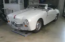 Panhard Dyna Junior X. In der unmittelbaren Nachkriegszeit gab es überall in Europa, also auch in Frankreich, Materialbeschränkungen. Dies war in allen Industriezweigen bis weit in die 1950`er Jahre spürbar. Während einige Hersteller der Automobilindustrie bei der Materialbelieferung Vorrang hatten, wie beispielsweise Renault, das mit seinem 4CV als erster Hersteller voll einsatzfähig war, mussten andere Hersteller warten und meist ihre überarbeiteten Vorkriegsfahrzeuge anbieten. In dieser tristen Automobillandschaft stach Panhard mit seinem Dyna X in seinem unverwechselbaren Stil und der Aluminiumkarosserie hervor. Von 1951 bis 1956 wurde auf dieser Basis ein hübscher, kleiner Roadster, der gezeigte Dyna Junior, gebaut. Ab 1954 wurde der vom Dyna X übernommene Kühlergrill mit der Kugel in der Mitte verbaut. In diesem Jahr wird die Version mit den vier Stuer-PS (4CV) eingestellt, so das nur noch das Cabrio im Handel bleibt. Der Zweizylinderboxermotor hat einen Hubraum von 851 cm³ und leistet 42 PS. Darüber hinaus kann das Modell mit einem MAG-Kompressor geordert werden. Mit dieser Option erhöht sich die Leistung auf 60 PS. Diese Motorleistung ist gut für eine Höchstgeschwindigkeit von rund 145 km/h. Classic Remise Düsseldorf am 09.06.2025.