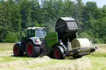 Fendt Allradschlepper mt Fendt Rundballenpresse Rotana 160V bei der Heuernte, der fertige Ballen wird nach hinten aus der Maschine gestoßen und dann auf dem Feld abgelegt, Juni 2025