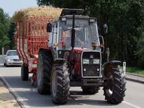 MF382 zieht nicht nur den Stroh beladenen Wagen, sondern auch eine ganze PKW-Kolonne hinter sich her; 090802