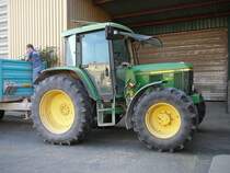 John Deere 6310 steht vor den Getreideentladung bei der Raiffeisenwarenzentrale in 36088 H�nfeld. Der auf der Anh�ngerdeichsel stehende Raiffeisenmitarbeiter nimmt eine Getreideprobe.