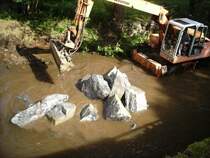 Der M1000 rumt die Steine, die der MAN abgekipt hat, auf die Seite.