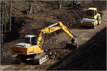 Whrend der Ein LIEBHERR 904 Litronic den Boden verteilt, verdichtet eine Vibrationswalze vom Hersteller BOMAG den Boden sofort...
