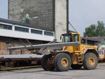 L110E ist mit der Entladung von Betonmasten am Bhf. Ried i.I. beschftigt;100430