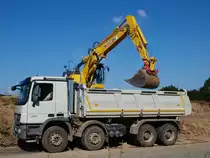 Hier wird ein blitzneuer Actros 3241 am 06.08.2010 auf der Campusbaustelle der RWTH in Aachen von einem Komatsu PC 228US Lc beladen. Die neuen Actros Lkw kann man gut an den Aussenspiegeln erkennen, die Kunstoffabdeckung ist mit Riffelblechoptik ausgestattet.  