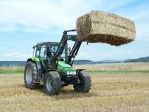 Deutz Fahr Agroxtra 4.57 hat einen Strohballen auf der Frontladergabel in Fulda-Dietershan, August 2010

