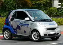 Blau-Grauer Smart mit Werbung unterwegs in der Stadt Zug am 20.08.2010