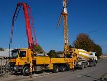 Eine Putzmeister M36 Betonpumpe auf Actros 2641 wird am 01.10.2010 in Aachen auf der Pauwelstrasse von einem Actros 3541 Betonmischer gefttert.