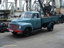 Opel BLITZ 1,75 t am 19.9.2010 Hafentreffen 2010 in Hamburg im Hafenmuseum Schuppen 50 / mit Hilsmitteln zur Verladung auf der Wasserseite des Schuppens /
1952 – 1960 / Pritschenwagen ohne Plane, kurzer Radstand 3.300 mm / 6-Zyl. 4-Takt Motor, 2473 cm, 58 PS, 62 PS ab 1955 / 3.800 kg zul. Ges.-Gewicht, 1.735 kg Leergewicht, 2.065 kg Nutzlast /
