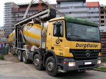 ACTROS-3236 bergibt die angelieferte graue Baumasse auf den im Hintergrund stehenden Mischwagen mit Betonpumpe;100827