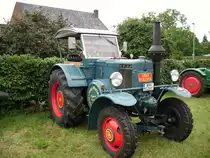 Lanz Gl�hkopf Bulldog
Der Arbeitsplatz des Bulldog Piloten. Es bedarf gro�er Muskelkraft den gro�en Lanz zu steuern, man sp�rt nebenbei bemerkt jeden Kolbenschlag und wird ger�ttelt und gesch�ttelt. Die Kupplung schwerg�ngig und die Schaltung hackelig. Ihn zu verz�gern, erfordert ausgepr�gte Muskulatur in den Beinen .Das Starten dieses Gl�hkopf Titanen ist nichts f�r schwache Gem�ter, sondern etwas f�hr absolute K�nner und �ber allem steht der Klang dieses riesigen Einzylinder Motor, dessen Kolben fast die Masse von Mutters Putzeimer aufweist. Wer Ihn einmal bewegt hat, wird es nie vergessen.