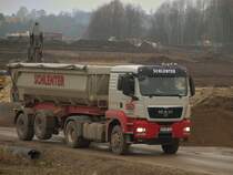 MAN TGS18.480 mit Kippersattelauflieger am 25.11.2010 auf der Campusbaustelle in Aachen. Der Fahrer hat gerade seine Ladung abgekippt und fhrt nun mit gehobener Liftachse zur Ladestelle zurck.