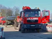 MAN TGM 13.250 mit MKG Kranaufbau der Firma Lube & Krings aus Aachen steht am 08.02.2011 mit einem Anhnger, auf dem 16m lange Rohre die hier fr das Fernwrmenetz verbaut werden sollen auf dem Seffenter Weg in Aachen auf der Campusbaustelle der Rwth.