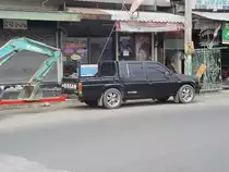 Nissan TL super mit Doppelkabine vor einem Hnger mit einem Minibagger beladen, am 14.02.2011 in Buri Ram / Thailand