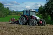 Steyr M-trac spezial 75, mit angebauter Scheibenegge bei der Arbeit, die Doppelbreifung erhht die Traktion, Aug.2011
