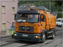 Hinter dem Asphaltfrser fhrt dieser MAN mit Staubsaugeraufbau, fegt und saugt den liegengelassen Rollsplitt in seinen Tank.  30.08.11 