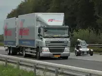 Ein DAF CF Tandemh�ngerzug wird am 20.09.2011 auf der A4 hinter dem Autobahnkreuz Aachen von einem Can-Am Spyder Roadster Touring �berholt. Das Dreirad wird von der Kanadischen Firma Bambardier Recrational Products gebaut. Mit einem 100PS Aprilia-Motor beschleunigt es von 0 auf 100 km/h in 5,5 Sekunden, die H�chstgeschwindigkeit ist 160 km/h, geschaltet wird per 5 Gang Fu�schaltung. Die Preise f�r das sportlichen Spa�ger�t beginnen bei 21 369 Euro.