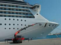 Wie ein kleines Insekt sieht der MAN TGA 41.440 mit Palfinger PK 150002 Schwerlastkranaufbau neben dem 292 meter langen Kreuzfahrschiff  Costa Atlantica  aus. An dem Kran ist eine Arbeitsbhne montiert in der zwei Arbeiter den Schiffsrumpf mit Farbe ausbessern. Gesehen am 06.10.2011 im Hafen von Rhodos(GR).