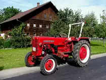 FARMALL D-320(1631ccm; Baujahr1958)parkt vor einem alten Holzhaus; 110814