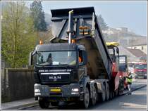 Strassenbauarbeiten in Wiltz. Der MAN Lkw hat sich vor den Asphaltfertiger gesetzt, hebt den Kipper und befllt so den hungrigen Rachen des Asphaltfertigers. 13.04.2012 