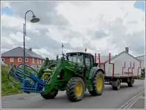 John Deere mit Rundballenzangenanbau am Frontlader mit H�nger, unterwegs um die gepressten Heuballen auf einem Feld abzuholen. 07.07.2012