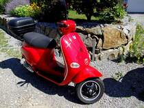 VESPA in roter Lackierung wurde vor einer Grantisteinmauer abgestellt; 120812