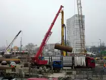Scania Autokran hebt am 10.04.2013 von einem MB Actros-Sattelzug auf der Baustelle der S21 am Bln.-Hbf. Eisenrohre die dann im Erdboden senkrecht versenkt werden.