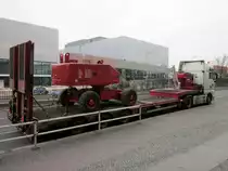 MAN TGX 18.680 mit Sattel-Tieflader. Beladen ist dieser Sattelzug mit einer fahrbaren Arbeitsbühne. Am hinteren Teil der Arbeitsbühne ist gut die Ketten-Sicherung über Kreuz zu sehen , vorne (nicht gut sichtbar) ebenfalls. Im Hintergrund des Bildes ein Teil der im Bau befindlichen  BMW NIEDERLASSUNG BERLIN  am Messedamm. 18.02.2014