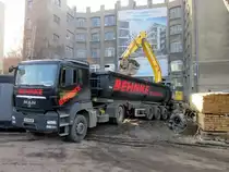 MAN TGS Kippsattelzug wird im Februar 2014 von einem New Holland Kettenbagger in Berlin-Charlottenburg mit Bauaushub beladen. 