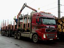 VOLVO-FH520, bei Nebelwetter werden mit dem aufgebautem Hydraulikkran Rundholzstämme aus Eisenbahnwaggons entladen; 140218