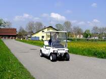 CLUB-CAR mit angebauter Seilwinde, surrt über einen frühlingshaften Güterweg; 140501