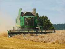 er zieht eine große Staubfontäne hinter sich her: John Deere 9880i auf einem Feld in 36100 Petersberg-Marbach im Juli 2014