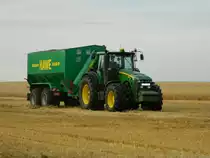 Traktor John Deere 8530 mit einem HAWE-Überladewagen am 04.07.2014 im Ernteeinsatz.