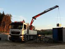 MAN TGS26.440 hebt eine Baustellenkiste auf seine Ladefläche; 141009